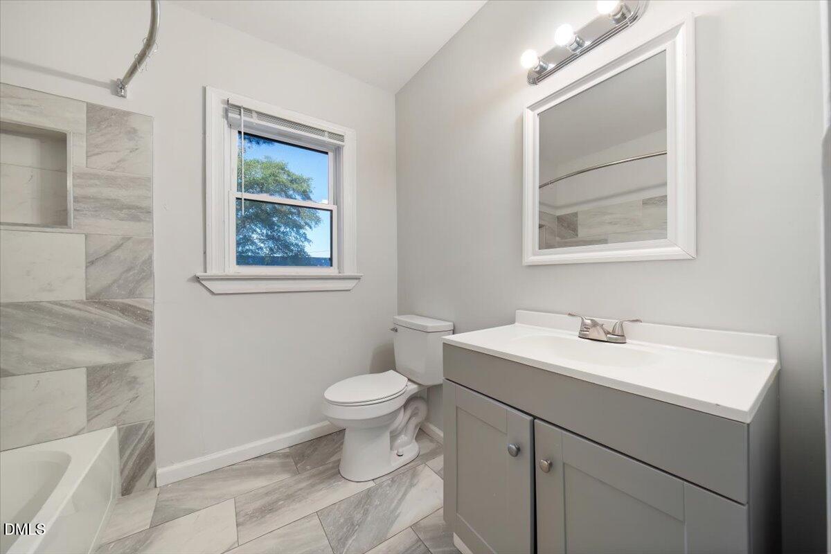1213 Tarboro Street Southwest Wilson, NC 27893 - Photo 16 of 27 a bathroom with a toilet sink vanity and mirror