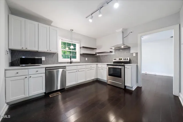 a kitchen with a white cabinets and wooden floor