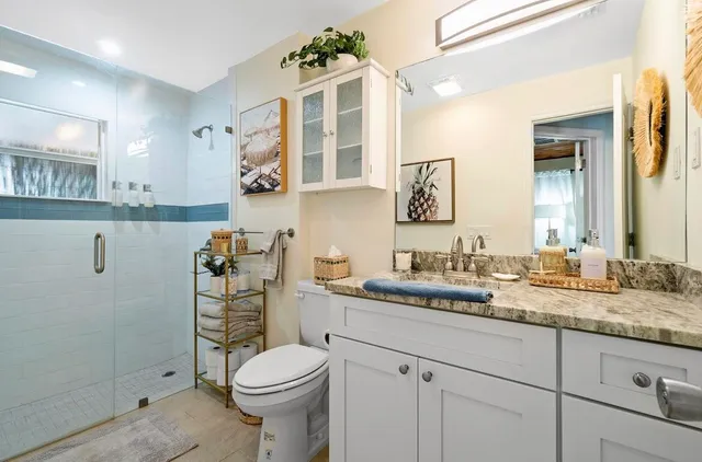 a bathroom with a granite countertop toilet sink and mirror
