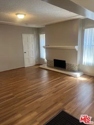an empty room with wooden floor fireplace and windows