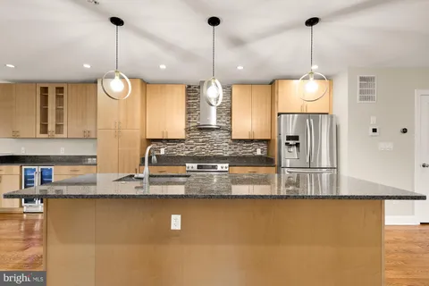 a kitchen with kitchen island granite countertop a stove a sink a island and windows