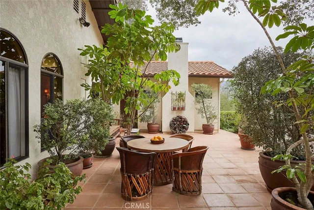 a view of a patio with table and chairs potted plants and floor to ceiling window