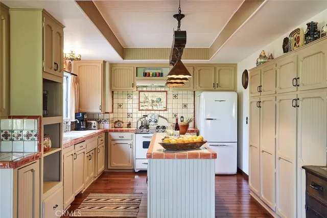 a kitchen with stainless steel appliances a stove refrigerator sink and wooden floor