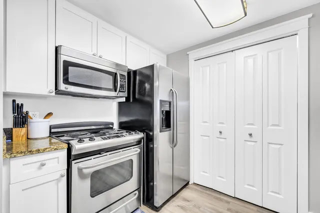 a kitchen with stainless steel appliances white cabinets and a stove top oven