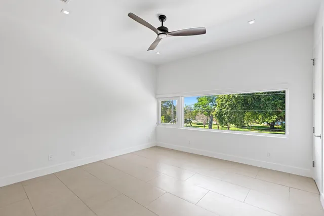 an empty room with a ceiling fan and windows