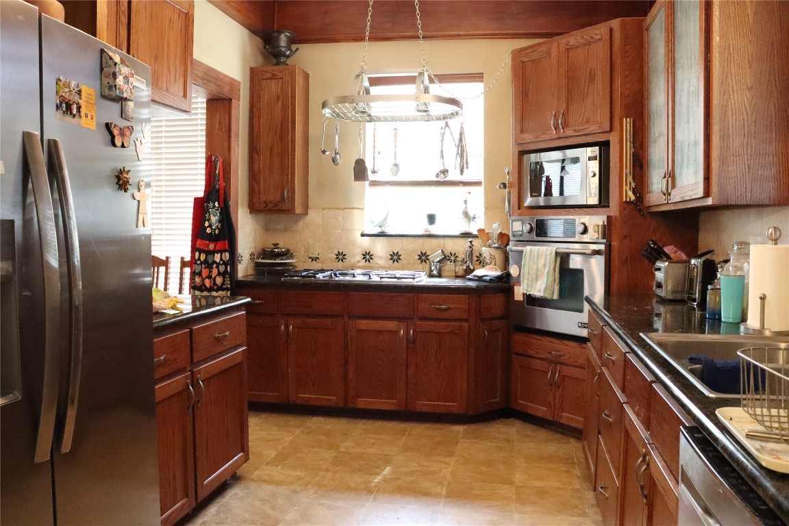 701 Sloan Street Taylor, TX 76574 - Photo 12 of 32 a kitchen with stainless steel appliances granite countertop a refrigerator a sink dishwasher a stove and white countertops with wooden floor