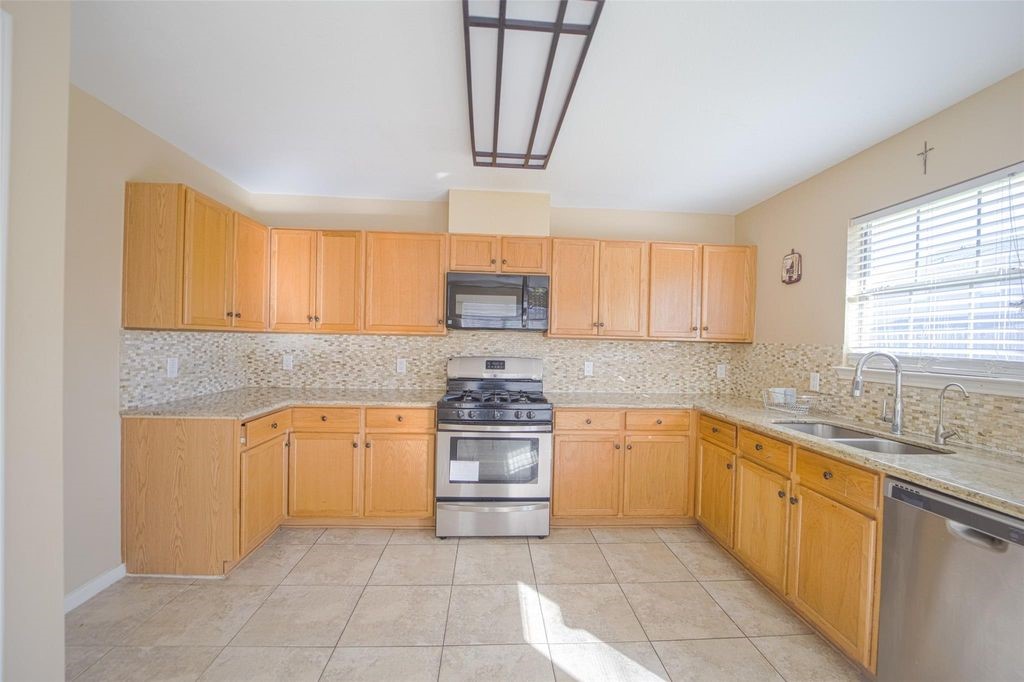 9611 Prairie Dog Run Sugar Land, TX 77498 - Photo 3 of 12 a kitchen with stainless steel appliances granite countertop a sink and a stove