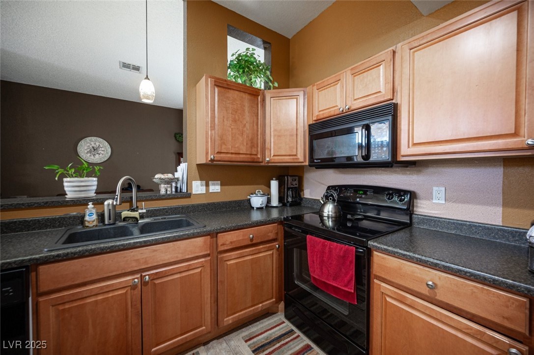 3150 North Soft Breezes Drive, Unit 2220 Las Vegas, NV 89128 - Photo 14 of 32 Kitchen featuring black appliances, dark countertops, and pendant lighting