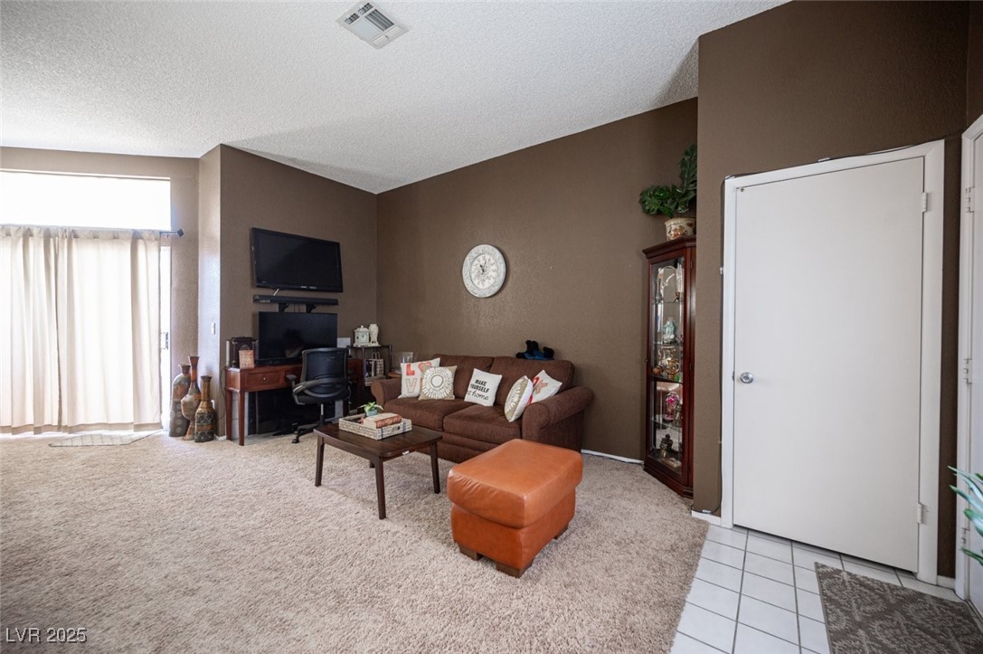 3150 North Soft Breezes Drive, Unit 2220 Las Vegas, NV 89128 - Photo 8 of 32 Living area with a textured ceiling, light tile patterned floors, light colored carpet, and a desk