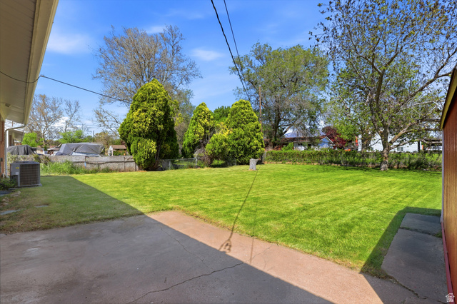 2348 North 770 West Clinton, UT 84015 - Photo 23 of 25 Expansive rear yard featuring a large grass lawn, mature trees, and a concrete patio