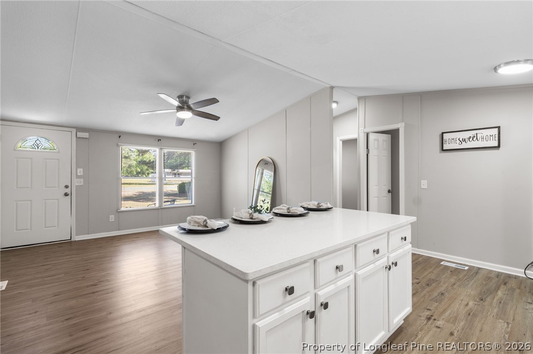 6568 Sandy Creek Road Stedman, NC 28391 - Photo 10 of 34 a kitchen with stainless steel appliances granite countertop a sink dishwasher and white cabinets with wooden floor