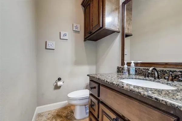a bathroom with a granite countertop sink a toilet and a mirror
