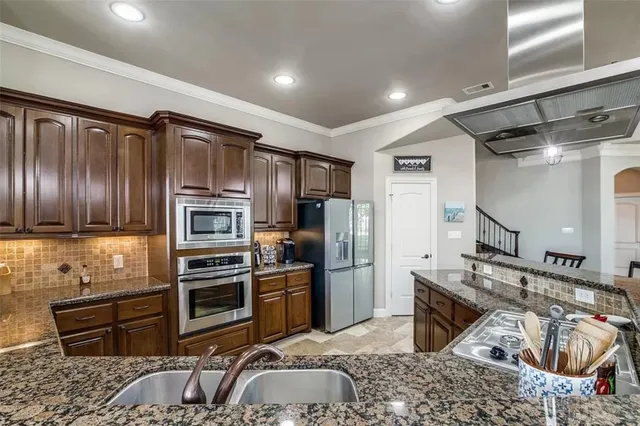 a kitchen with stainless steel appliances granite countertop a sink stove and refrigerator