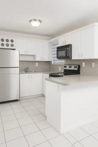 a kitchen with a refrigerator a stove top oven and white cabinets