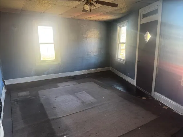 an empty room with windows and fan