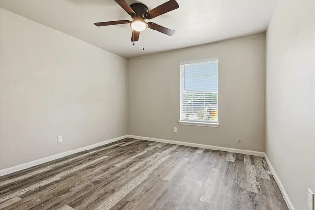 an empty room with a window and ceiling fan