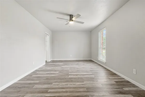 a view of an empty room with wooden floor and a window