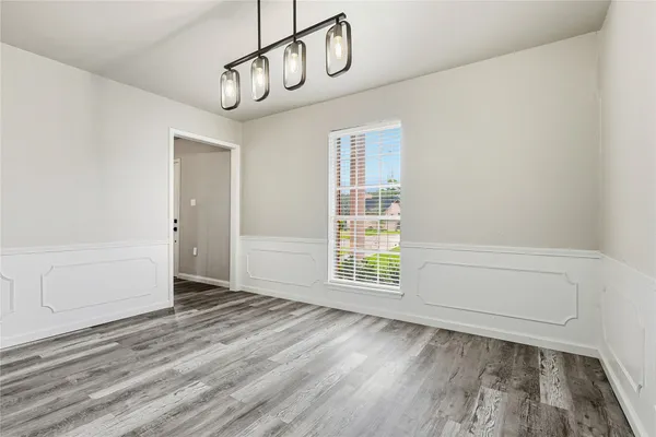 a view of an empty room with wooden floor and windows