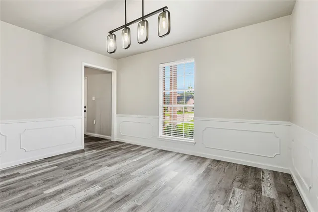 a view of an empty room with wooden floor and windows