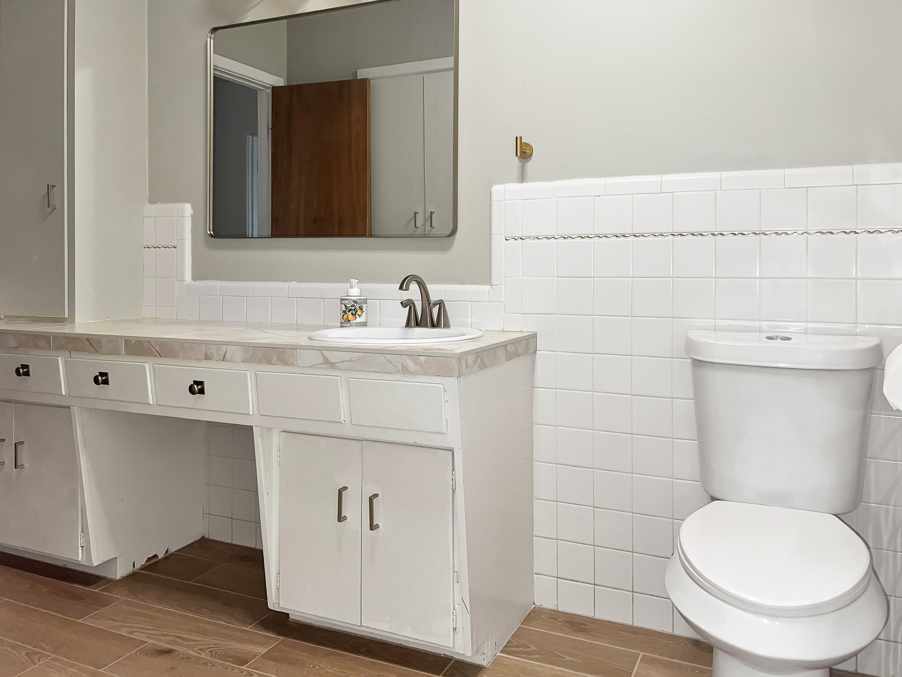 3827 52nd Street Lubbock, TX 79413 - Photo 13 of 24 a bathroom with a toilet a sink and mirror