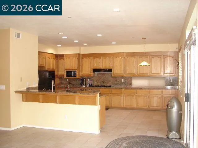 a kitchen with stainless steel appliances granite countertop a refrigerator a stove and a microwave with wooden floor