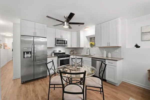 a kitchen with stainless steel appliances a table chairs microwave and refrigerator