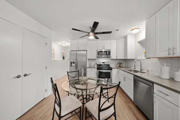 a kitchen with stainless steel appliances a table chairs refrigerator and microwave