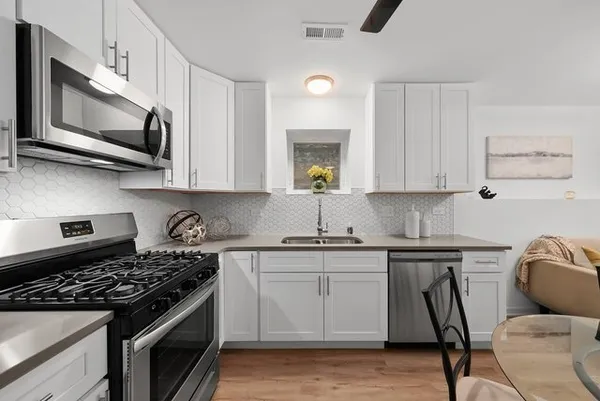 a kitchen with stainless steel appliances a stove a microwave a sink and cabinets