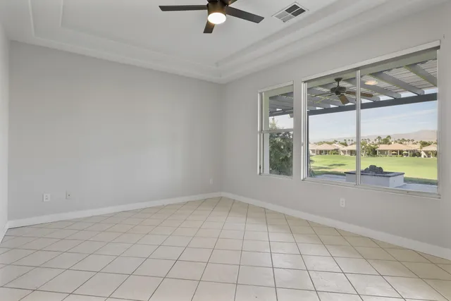 a view of an empty room and chandelier fan