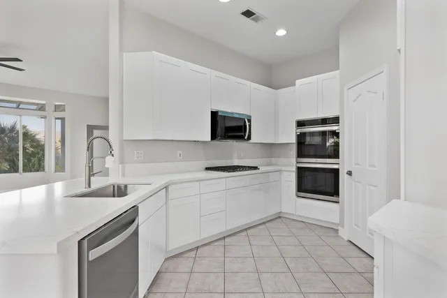 a kitchen with stainless steel appliances a sink a stove a refrigerator and cabinets
