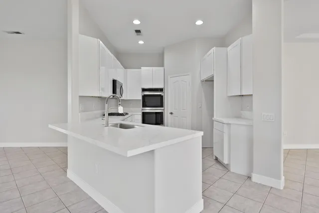 a kitchen with white cabinets and sink