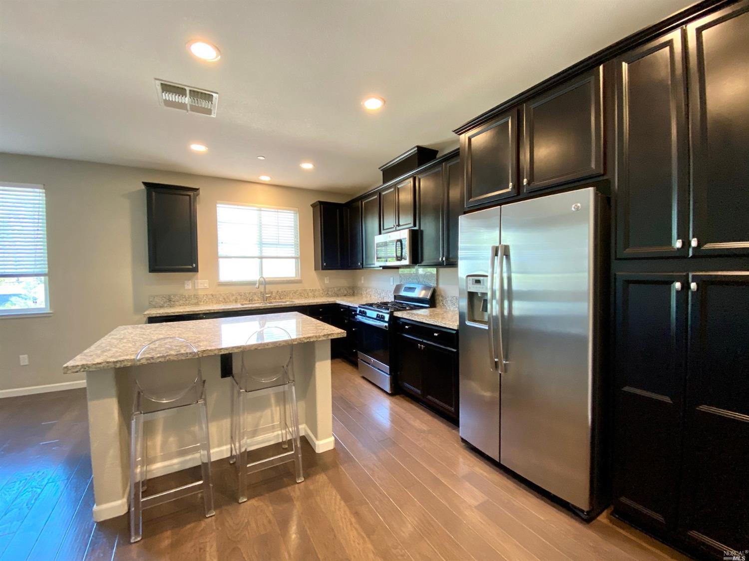 a kitchen with stainless steel appliances granite countertop a refrigerator a sink and a stove top oven