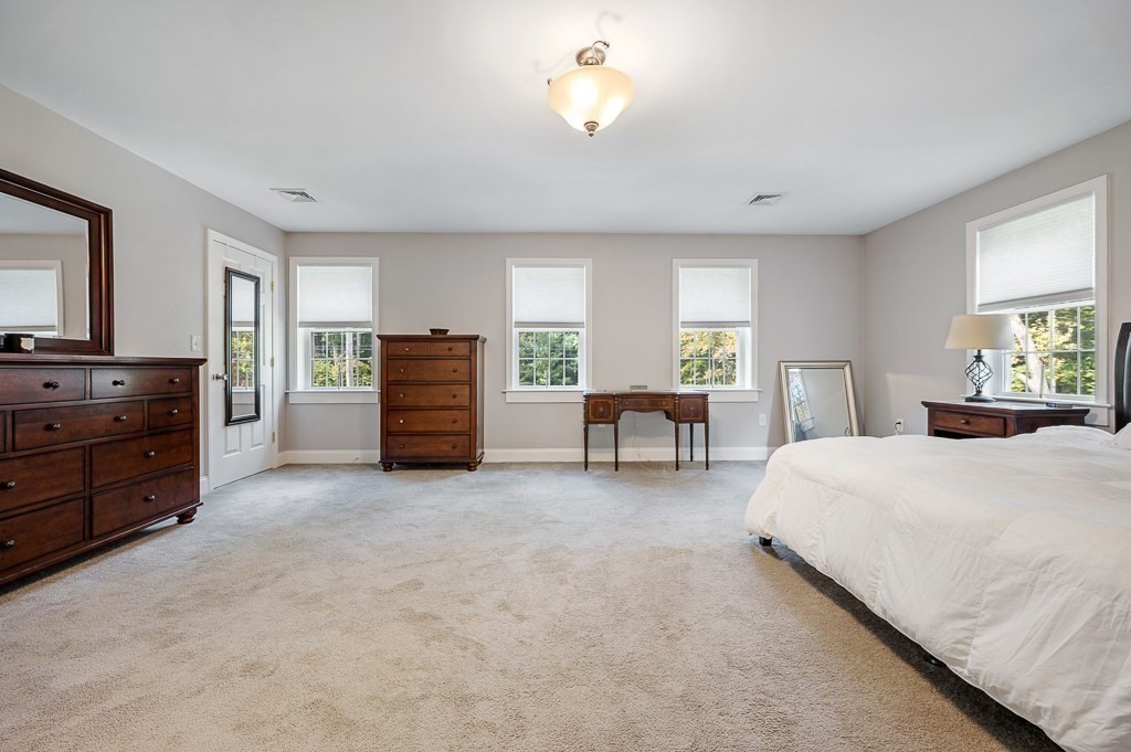 173 Podunk Road Sturbridge, MA 01566 - Photo 21 of 40 a spacious bedroom with a bed and a chandelier