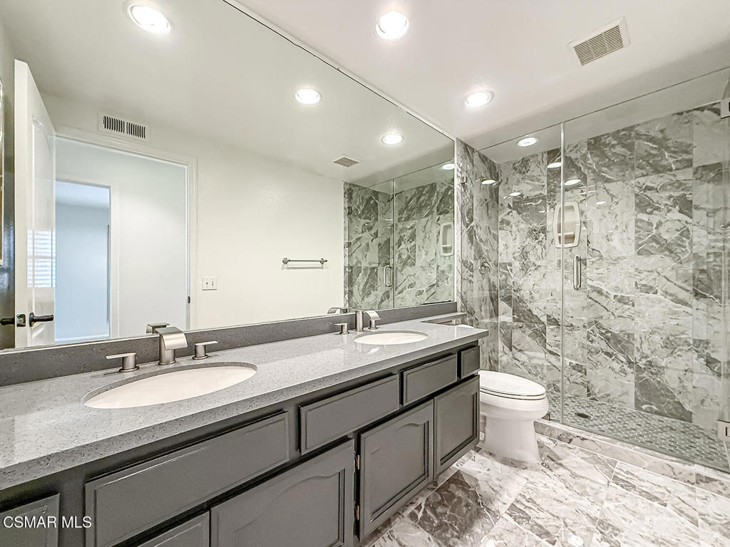 12057 Falcon Crest Way Porter Ranch, CA 91326 - Photo 41 of 86 a bathroom with a granite countertop sink a toilet and a mirror