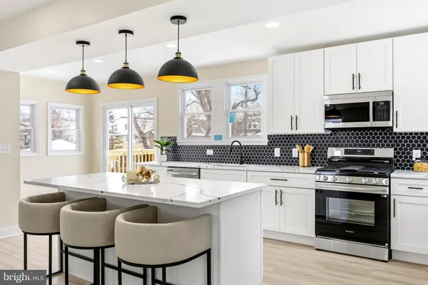 a kitchen with stainless steel appliances a stove a sink a microwave a dining table and chairs