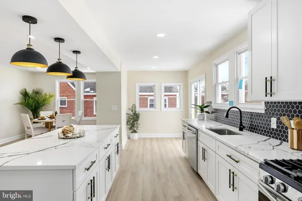 a kitchen with sink stove and white cabinets with wooden floor