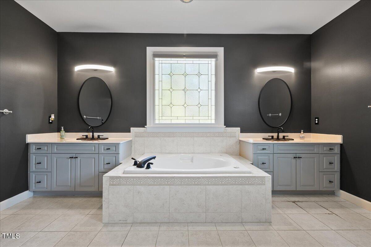 1005 Bellewood Farms Road Raleigh, NC 27603 - Photo 18 of 61 a bathroom with a tub a double vanity sink and mirror