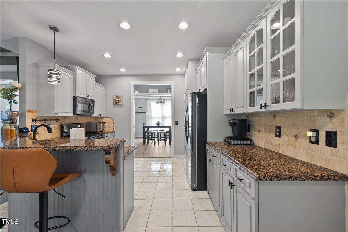 1005 Bellewood Farms Road Raleigh, NC 27603 - Photo 30 of 61 a kitchen with stainless steel appliances granite countertop a sink a stove a refrigerator cabinets and living room view