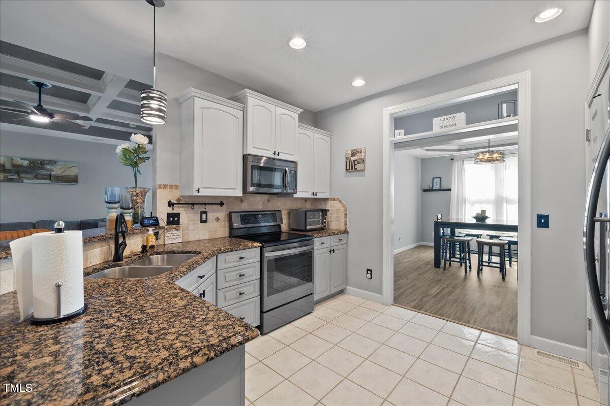 1005 Bellewood Farms Road Raleigh, NC 27603 - Photo 31 of 61 a kitchen with stainless steel appliances granite countertop a stove top oven a sink dishwasher a dining table and chairs with wooden floor