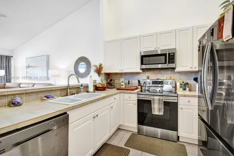 a kitchen with stainless steel appliances granite countertop a refrigerator sink and white cabinets