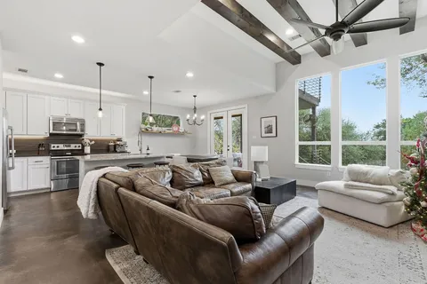 a living room with furniture and a large window with kitchen view