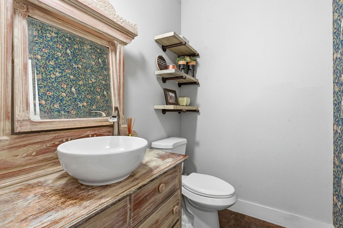 10012 Janet Loop Dripping Springs, TX 78620 - Photo 25 of 38 a bathroom with a granite countertop toilet a sink and a mirror
