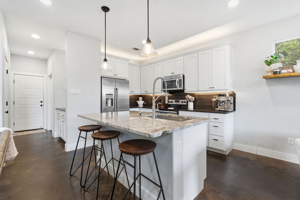 10012 Janet Loop Dripping Springs, TX 78620 - Photo 4 of 38 a kitchen with stainless steel appliances granite countertop a sink a stove a refrigerator and island with wooden floor