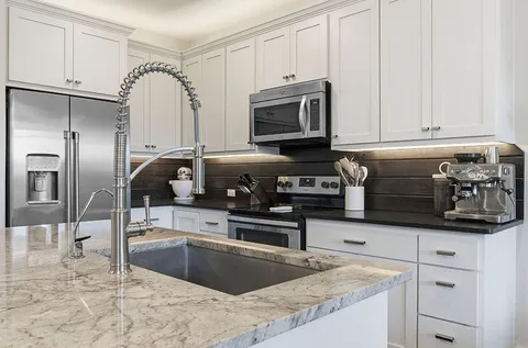 a kitchen with stainless steel appliances granite countertop a sink a stove and a refrigerator