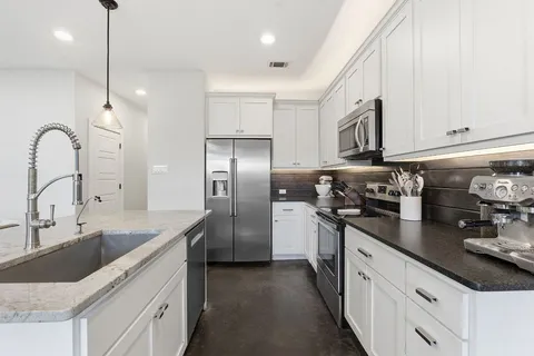 a kitchen with stainless steel appliances granite countertop a sink stove and refrigerator