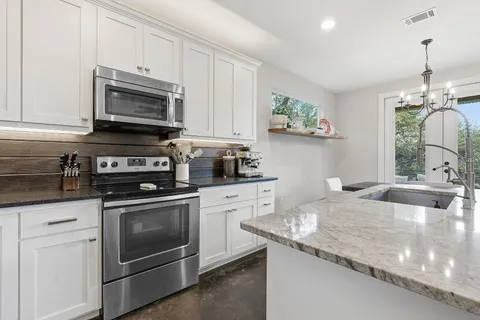 a kitchen with granite countertop a stove sink and microwave