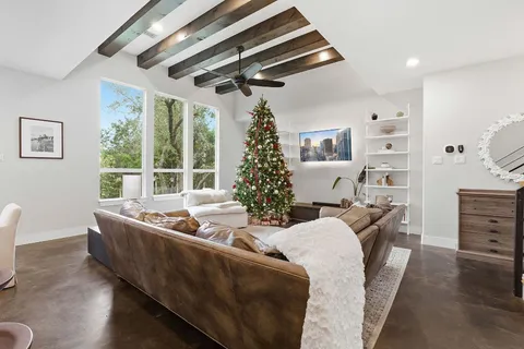 a living room with furniture large window and wooden floor