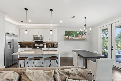 a kitchen with stainless steel appliances kitchen island granite countertop a table chairs and a refrigerator
