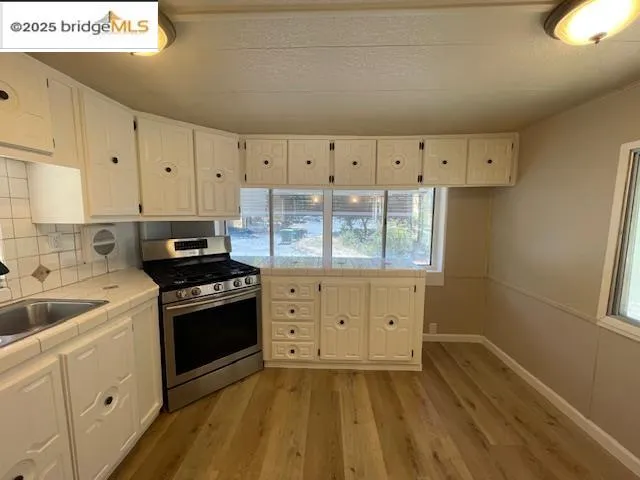 a kitchen with granite countertop a stove a sink and a refrigerator