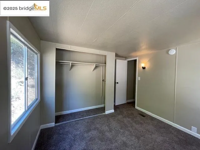 a view of an empty room with window and bathroom